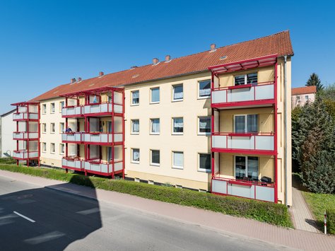 Wohnblock mit heller Fassade und roten Balkonen