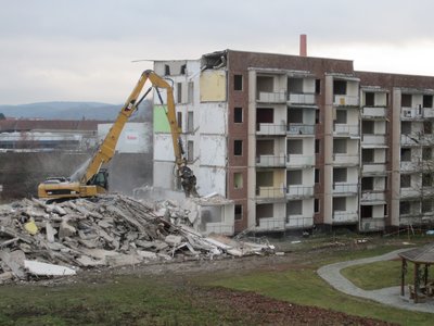 Bagger steht auf dem Bauschutt eines abgerissenen Wohngebäudes