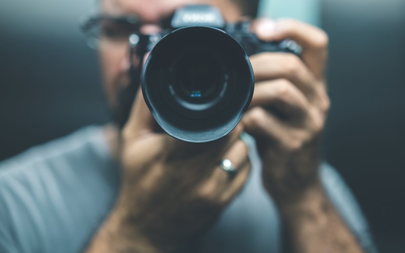 Mann hält seine Spiegelreflexkamera ans Gesicht zum Fotografieren