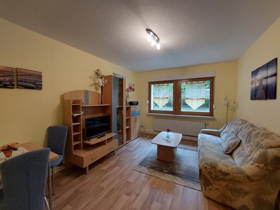 Wohnzimmer mit Couch, Fernseher und kleinen Esstisch