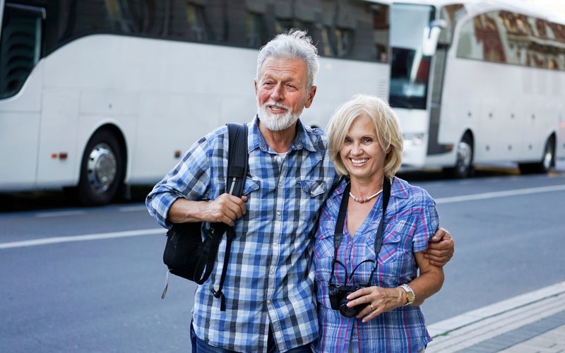 Älteres Paar vor zwei Reisebusen